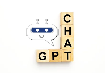 Ilustração de um robô sorridente em um balão de fala ao lado de blocos de madeira formando a palavra CHAT GPT, em fundo branco